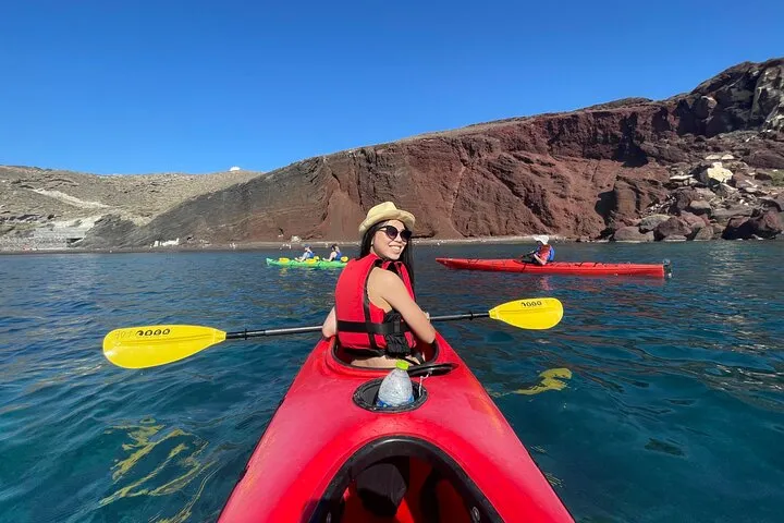 Sea kayaks below red volcanic cliffs on a Santorini sea kayak tour, Santorini Greece