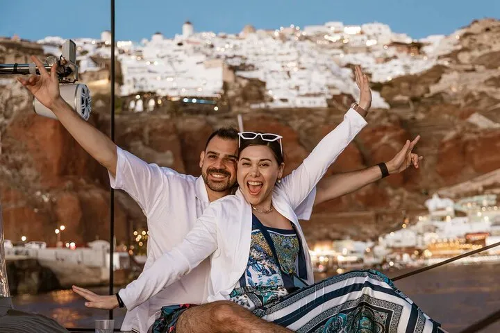 Catamaran cruising along the caldera cliffs at sunset with swim stops, Santorini Greece