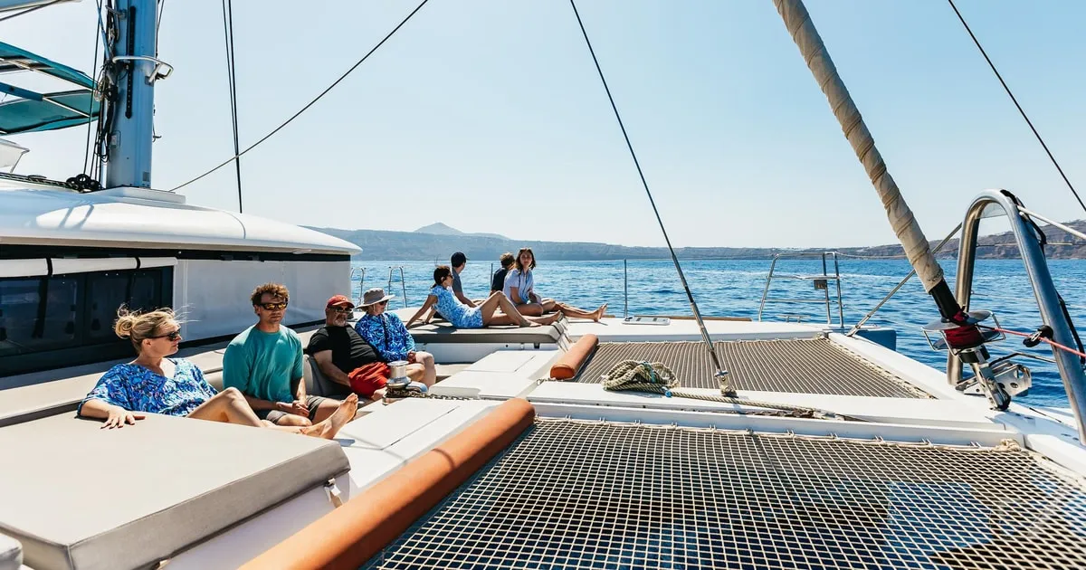 Luxury catamaran anchored off the volcanic coast on a Santorini day trip, Santorini Greece